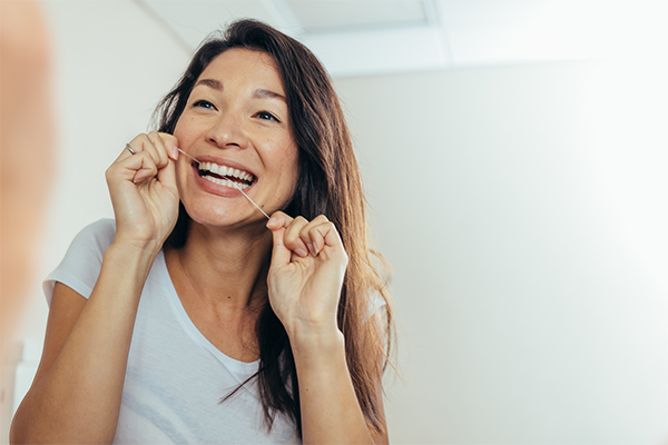 Kvinna förebygger tandlossning med tandtråd
