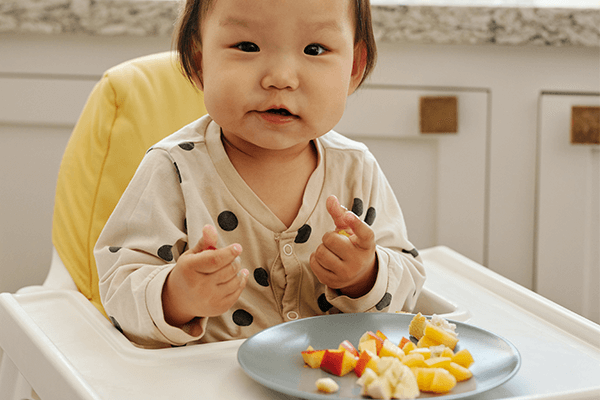 Litet barn som äter frukt som innehåller c-vitamin