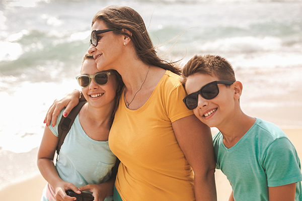 Familj som smörjt in sig med solskydd på stranden