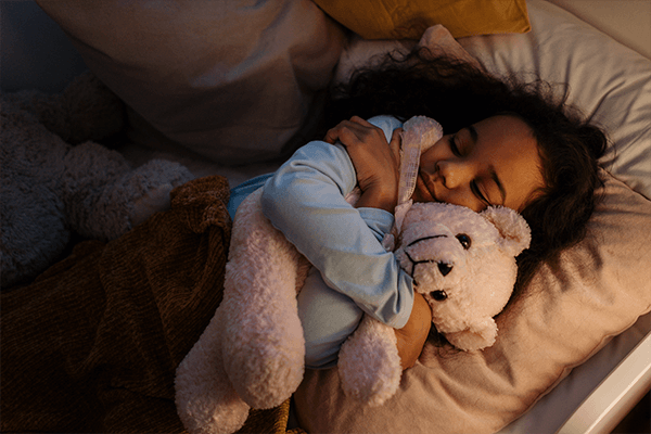 Barn som sover med sin nallebjörn
