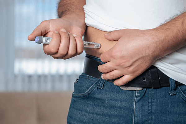 Man med diabetes som tar insulinspruta