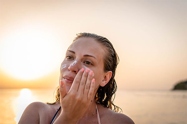 Kvinna smörjer ansiktet med solkräm