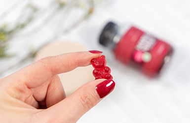 Hand som håller i en gummy med vitayummy-produkt i bagrunden.